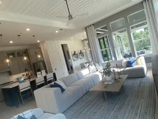 A spacious living area with cozy seating, elegant pendant lights, and large windows offering natural light and outdoor views.