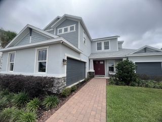 A two-story home with a stylish stone and shingle combination, welcoming front entry, and lush landscaping at River Landing by Taylor Morrison (Wesley Chapel, FL).