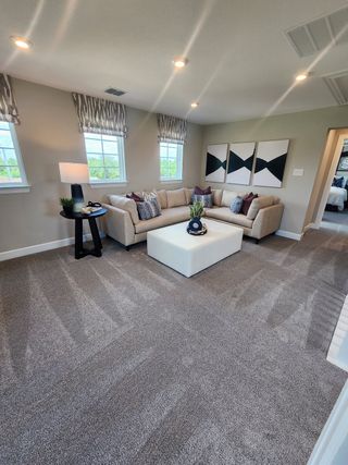 Model Home A cozy living area with plush carpeting, a sectional sofa, geometric art, and modern lighting.