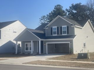 A charming gray two-story home in Lindera Preserve at Cane Bay Plantation (Summerville, SC) by Lennar, boasts a modern design with a spacious garage.