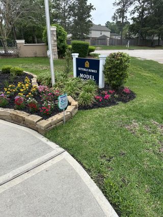 Beautiful landscaped entrance with vibrant flowers at Stewart’s Forest by Sitterle Homes in Conroe, TX.