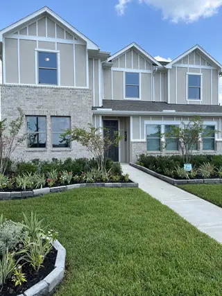 A charming gray and white home with lush landscaping in Windcress by Coventry Homes (Cove, TX).