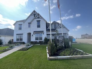 Street view A charming brick exterior with modern black accents and lush landscaping in Solterra Texas by Coventry Homes (Mesquite, TX).
