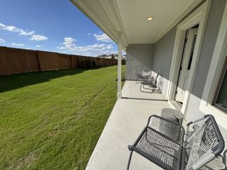 A serene backyard patio with sleek patio chairs and a spacious grassy lawn, perfect for relaxation and outdoor enjoyment.