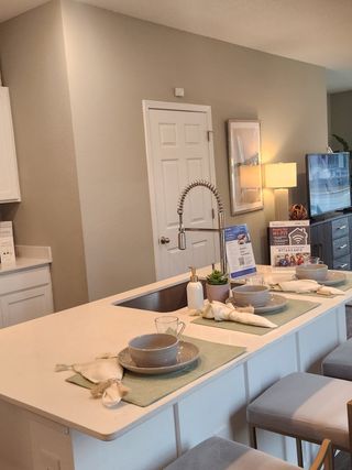 Model Home A cozy kitchen space featuring a sleek island with elegant dinnerware, a gooseneck faucet, and ambient lighting.
