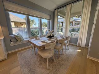 Model Home A bright and welcoming dining room featuring a wooden table, comfortable chairs, and large windows with scenic views.