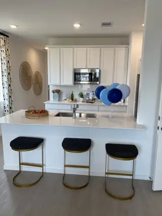 Sleek kitchen with white cabinetry, modern appliances, and a chic island with stylish stools and decorative accents.