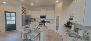 A modern kitchen with granite countertops, white cabinets, and an inviting island for dining.