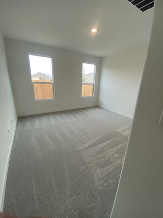 Model Home A bright, cozy room with clean carpet, large windows, and soft lighting for a welcoming atmosphere.