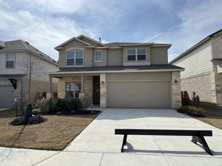 A charming two-story home with stone accents and a cozy porch in Meyer Ranch by Princeton Classic Homes (New Braunfels, TX).