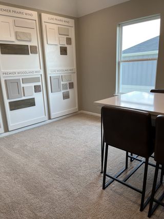 A cozy room with carpet flooring, a modern table and chairs, and design sample boards on the wall.