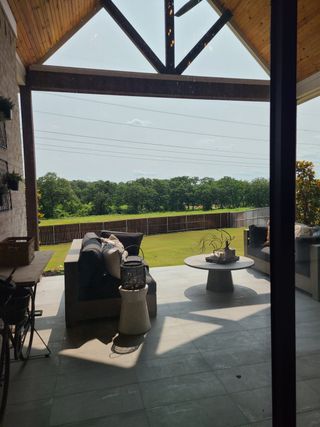 A cozy patio with modern sofas, chic decor, and lush lawn views ideal for relaxation.