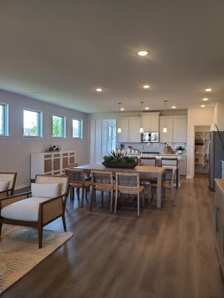A spacious open-concept dining area with elegant wooden floors, cozy seating, and modern pendant lighting.