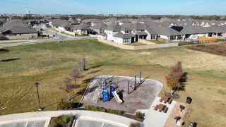 A well-equipped playground in The Colony, featuring slides, swings, picnic tables, and open green space for families to gather.
