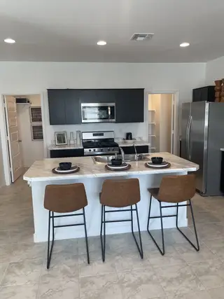 Modern kitchen with sleek dark cabinets, stainless steel appliances, and a marble-topped island featuring chic bar stools.
