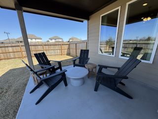 A cozy patio with black Adirondack chairs, white round table, and a wooden fence providing a private outdoor retreat.