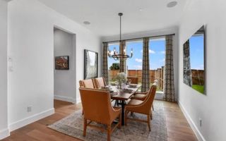 Model Home A chic dining room with a wooden table, elegant chairs, a chandelier, and large windows with flowing curtains.