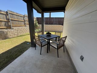 A cozy patio with a modern table set, surrounded by a wooden fence and well-maintained lawn.
