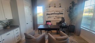 A contemporary office with chic decor, featuring a sleek desk, plush chairs, and abstract art on the wall.