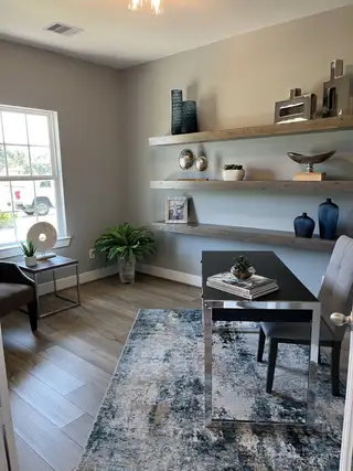 A modern office space with sleek furnishings, wooden shelves, elegant decor, and a large window for natural light.