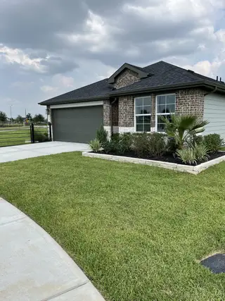 Street view A charming brick home with a manicured lawn in Summerview by M/I Homes (Fulshear, TX).