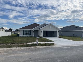 Street view A charming single-story home with a neat lawn and a two-car garage in Oak Hill Plantation by Adams Homes (Ocala, FL).