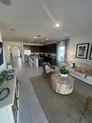 An open-concept living space featuring a cozy seating area, rustic coffee table, and modern kitchen with bar seating.