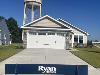 A charming single-story home with stone accents and a lush lawn in Somerset Two-Story Homes by Ryan Homes (Santee, SC).