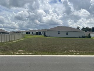 Street view A serene suburban street view of JB Ranch by D.R. Horton in Ocala, FL, showcasing modern homes and expansive lawns.