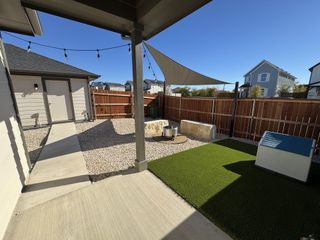 A charming backyard with patio, string lights, and artificial turf. Perfect for outdoor relaxation and entertaining.