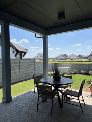 Model Home A cozy covered patio with wicker furniture and a view of a sunny yard, perfect for outdoor relaxation.