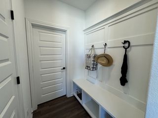 Model Home A stylish mudroom with built-in storage, white paneling, and convenient hanging hooks.