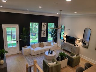 A modern living room featuring a bold black accent wall, chic mirrors, plush seating, and stylish decor accessories.