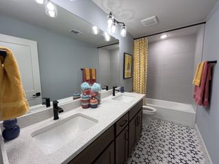 A stylish en-suite bathroom featuring a double vanity, elegant lighting, and modern finishes in Solterra by David Weekley Homes (Mesquite, TX).