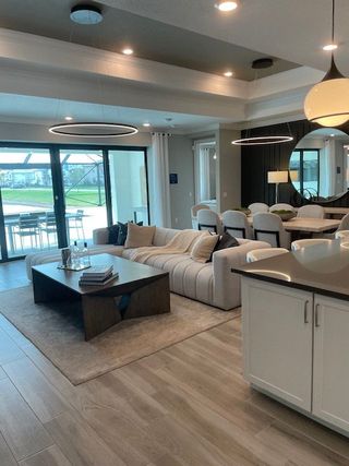 A modern living space with an open layout, featuring a sleek sectional, stylish dining area, and large glass doors to the patio.