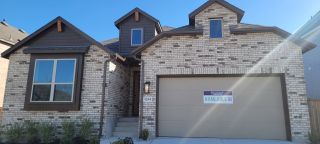 A newly constructed brick home in VIDA by Highland Homes (San Antonio, TX) with dark trim.