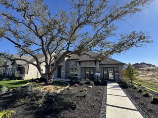Model Home Charming stone home with a sprawling tree and landscaped yard in The Cottages at La Cima by Ashton Woods (San Marcos, TX).