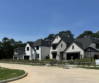 Charming white brick homes with manicured yards in Brook Bend at Clopton Farms by Tri Pointe Homes (Conroe, TX).