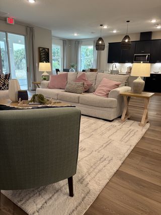 A cozy open-concept living area with plush sofas, elegant lighting, and a sleek kitchen.