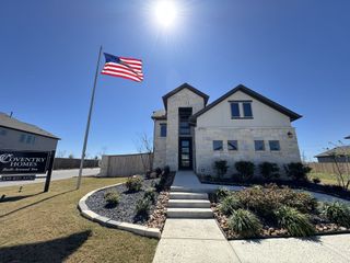 A modern stone home with lush landscaping in The Parklands by Coventry Homes (Schertz, TX).