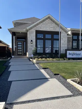 A modern brick home with a sleek pathway and manicured lawn in Solterra Texas by Brightland Homes (Mesquite, TX).