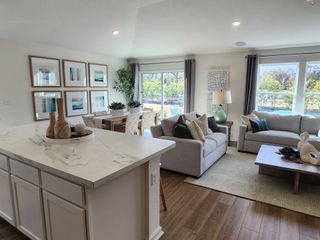 A modern living room with cozy sofas, a marble island, chic decor, and abundant natural light pouring through large windows.