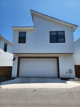 Street view A modern white home with a unique roofline and garage in Coopers Square by Legacy Communities (Austin, TX).