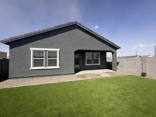 Street view A modern gray home with a neat lawn in Agave Trails by Starlight Homes (Buckeye, AZ).