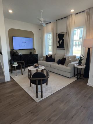 A modern living room with sleek furniture, warm wooden flooring, and elegant decor in neutral tones.