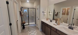 A modern bathroom with a double vanity, sleek black fixtures, and a glass-enclosed shower.