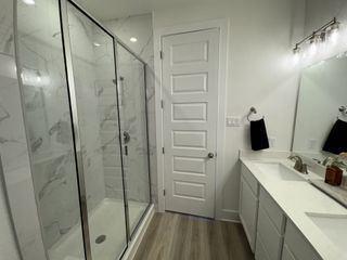 A sleek bathroom featuring a glass-enclosed shower, quartz vanity, and modern lighting fixtures.