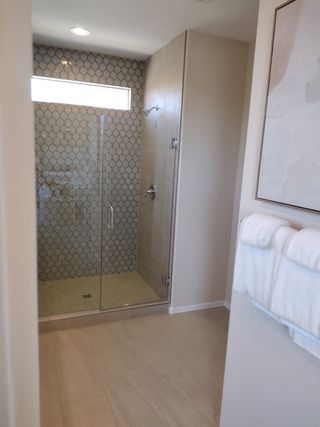 A sleek bathroom with a geometric-tiled shower, glass door, and soft lighting for a modern touch.