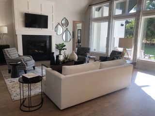 A contemporary living room featuring a white sofa, patterned chairs, and large windows with a view of the backyard.