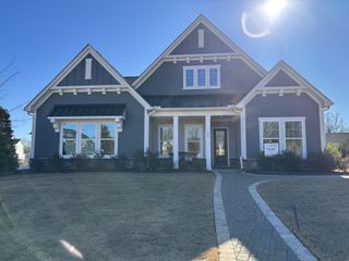 Street view A charming grey home with a welcoming porch and manicured lawn in McLean South Shore by Tri Pointe Homes (Belmont, NC).